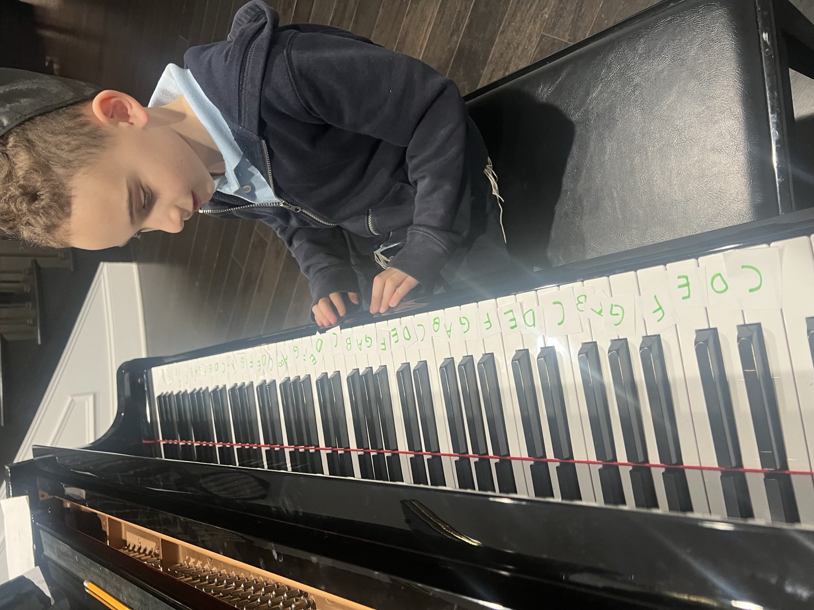 Student learning note names at the piano